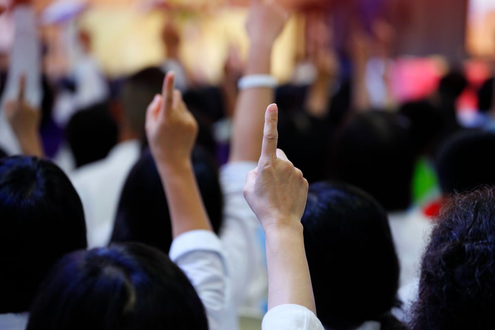 individuals raise hands indicating vote in favor